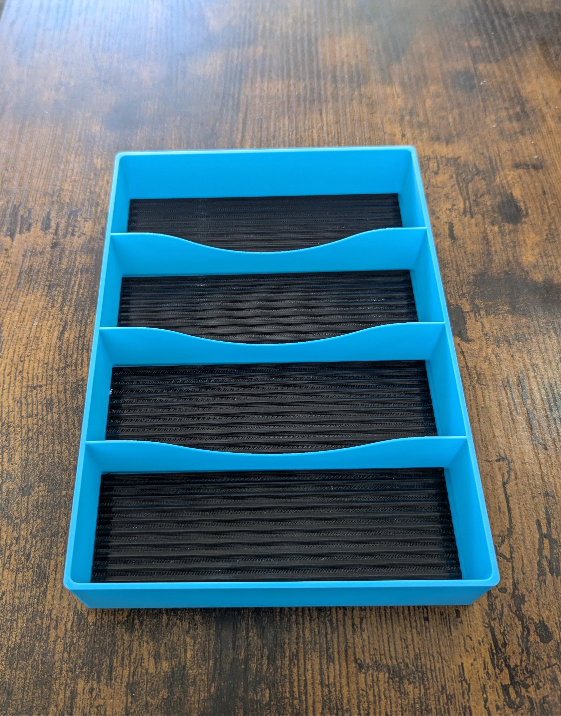 Blue plastic tray with black compartments on a wooden surface