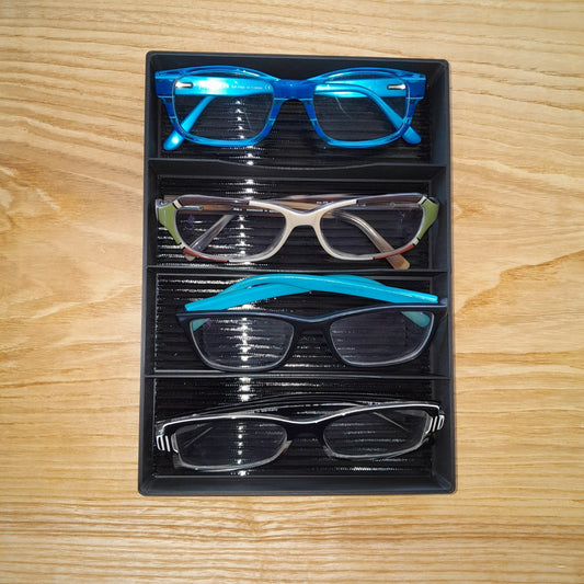 Set of eyeglasses in a black tray on a wooden surface